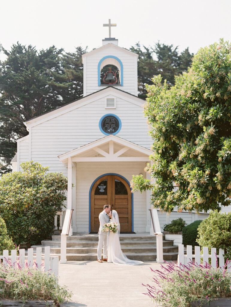 Bride and groom portrait in front of Saint Anthony's Catholic Church in Mendocino, California, by destination wedding photographer, Bethany Erin Photography.