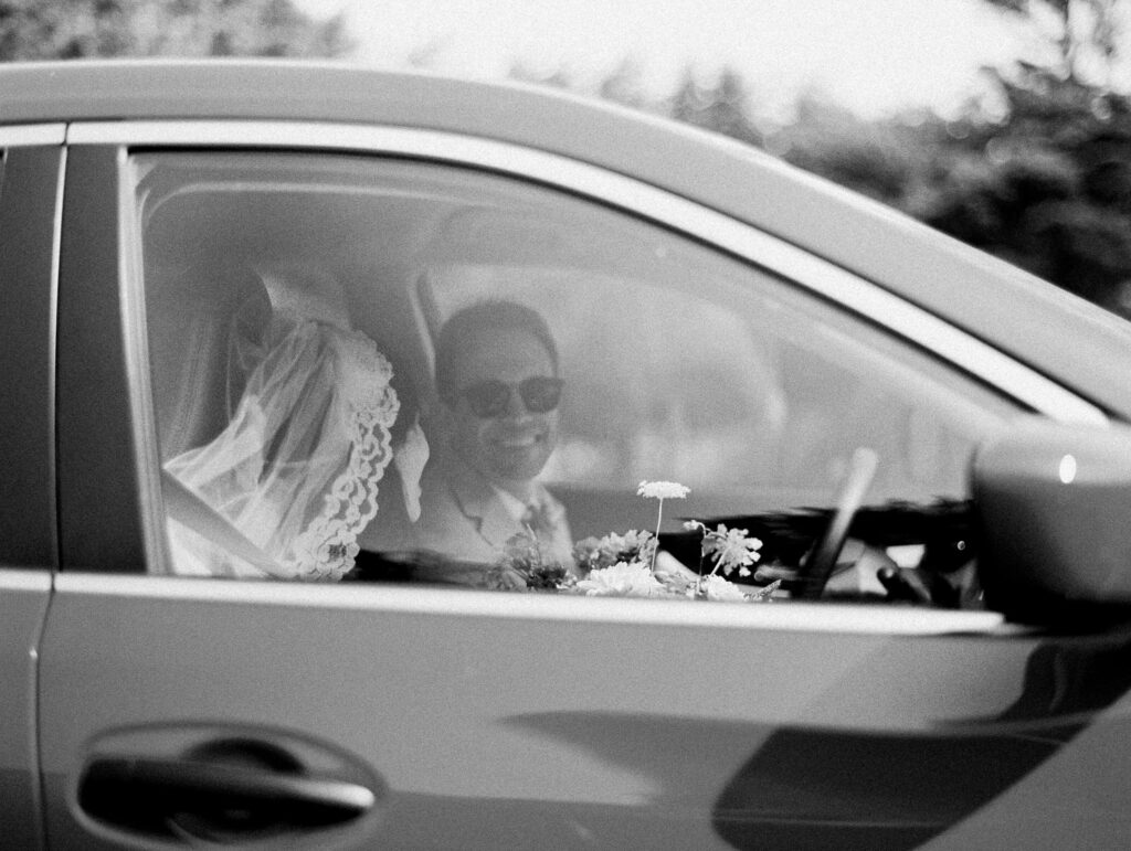 Candid moment of bride and groom in car leaving Saint Anthony's Catholic Church in Mendocino, California, by destination wedding photographer, Bethany Erin Photography.