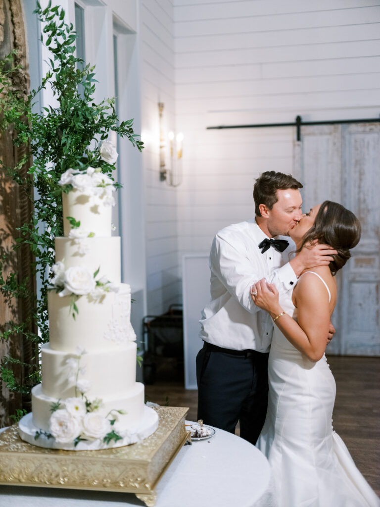 Bride and groom kiss after cutting the cake, photographed by Dallas Wedding Photographer, Bethany Erin Photography. 